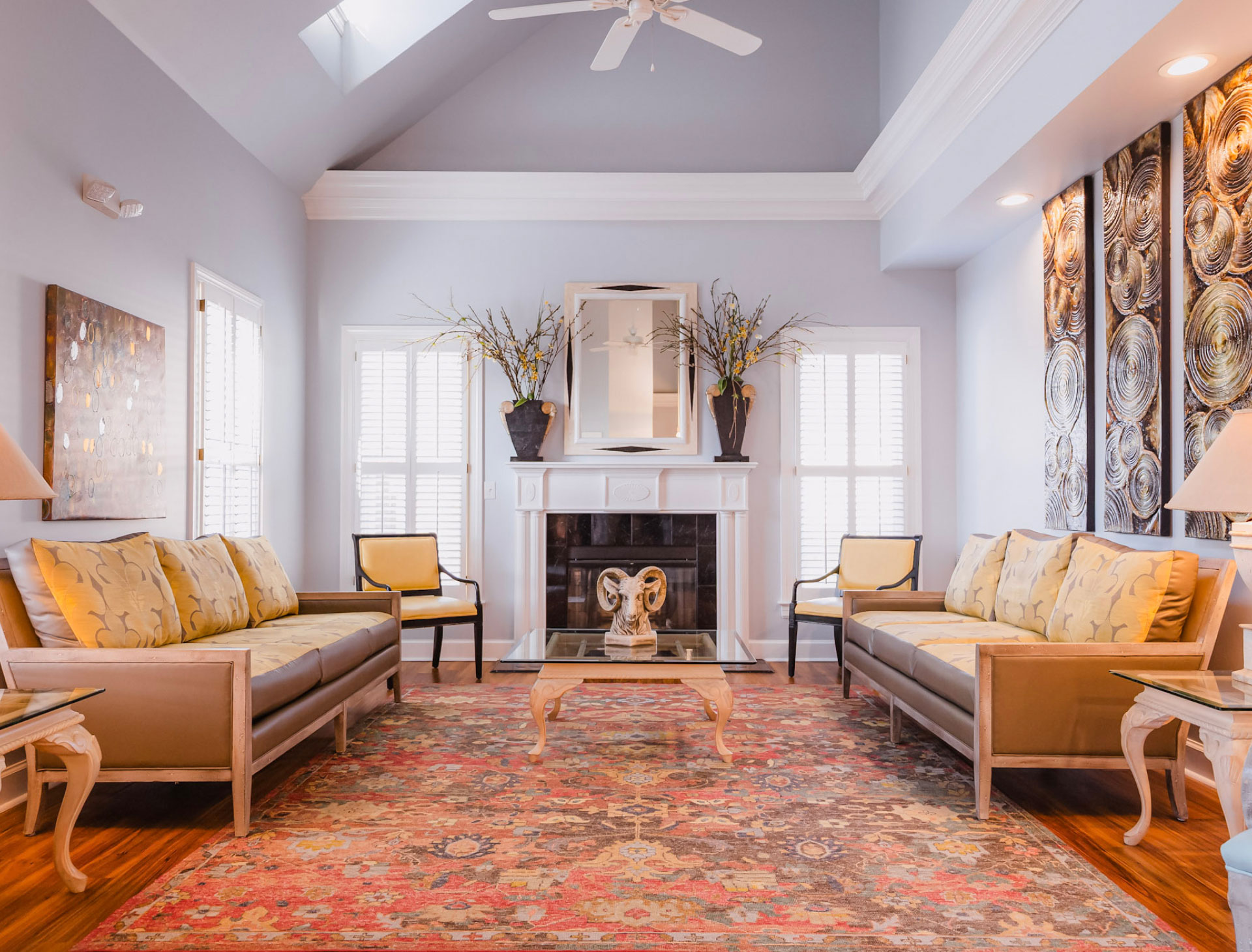 reception area with couches and chairs for seating and fireplace with large plants and mirror on the mantel in the middle